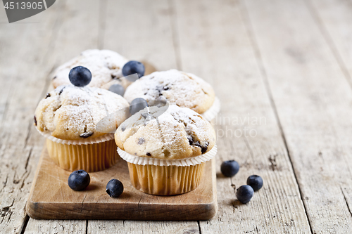 Image of Four homemade fresh muffins with blueberries on rustic wooden ta