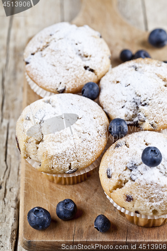 Image of Four homemade fresh muffins with blueberries on rustic wooden ta