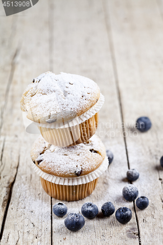 Image of Two fresh homemade muffins with blueberries on rustic wooden tab