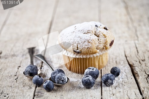 Image of Homemade fresh muffin with sugar powder, vintage spoons and blue