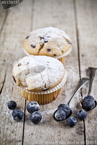 Image of Two homemade fresh muffins with sugar powder, vintage spoons and