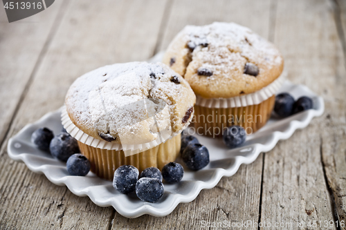 Image of Homemade fresh muffins with sugar powder and blueberries on cera