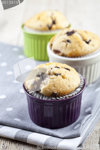 Image of Three homemade fresh muffins on colorful ceramic bowls on linen 