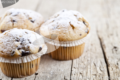 Image of Homemade fresh muffins with sugar powder closeup on rustic woode