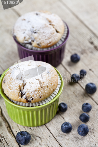 Image of Two homemade fresh muffins on ceramic green and purple bowls wit