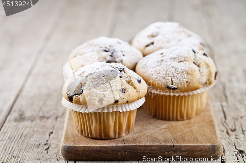 Image of Four homemade fresh muffins with sugar powder and blueberries on