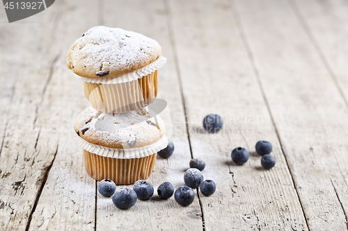 Image of Two fresh homemade muffins with blueberries on rustic wooden tab
