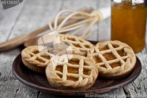 Image of Fresh baked tarts with marmalade or apricot jam filling and on c