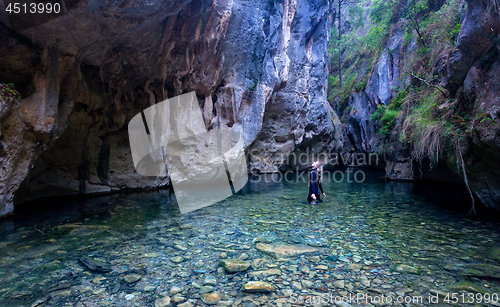 Image of Female looks up in awe admiring the canyon walls and caves high 