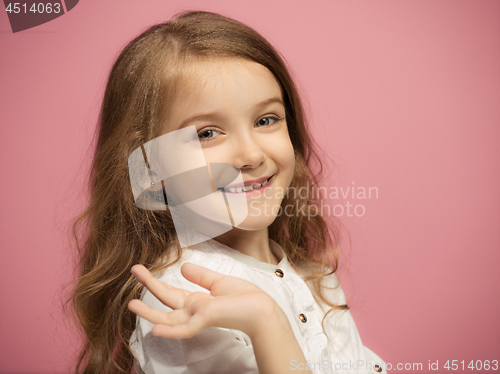 Image of The happy teen girl standing and smiling against pink background.