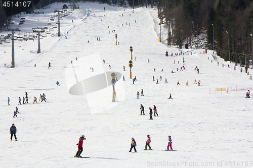 Image of Lots of skiers and snowboarders on the slope at ski resort 
