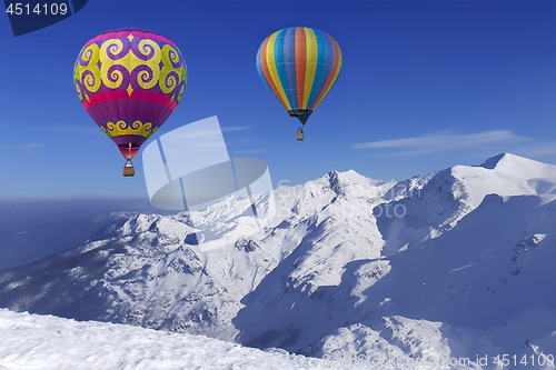 Image of Colorful balloons flying over snow-covered mountains