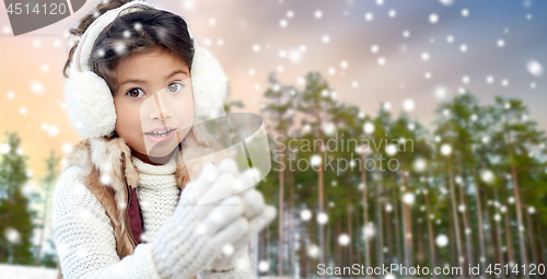 Image of little girl wearing earmuffs over winter forest