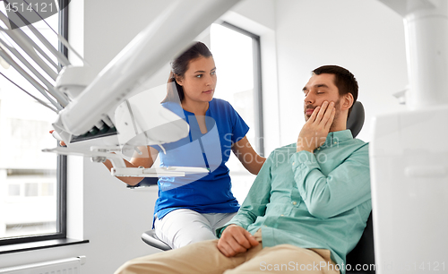 Image of man with toothache and dentist at dental clinic