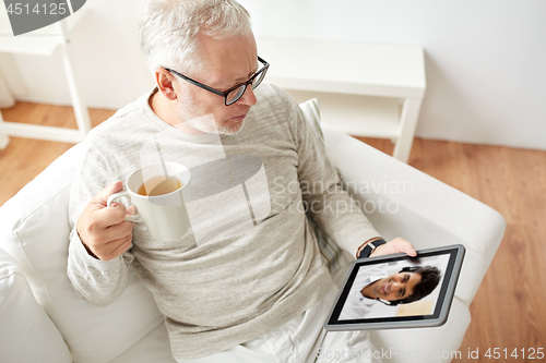 Image of senior man having video call on tablet pc at home