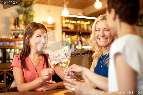 Image of happy women drinking wine at bar or restaurant