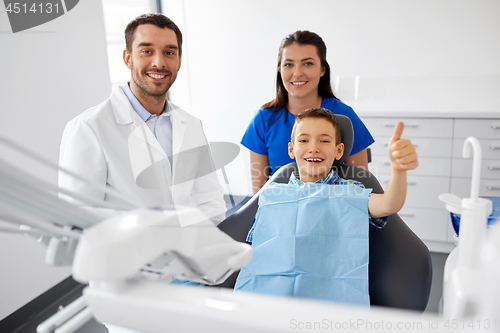 Image of dentist and boy showing thumbs up at dental clinic