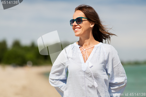 Image of happy smiling woman in sunglasses on summer beach