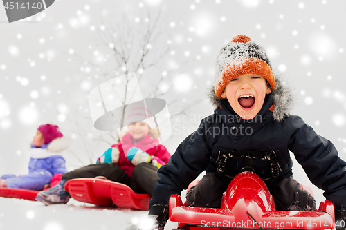 Image of happy kids sliding on sleds in winter