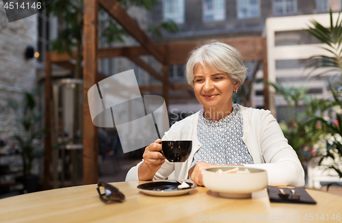 Image of senior woman drinking coffee at street cafe