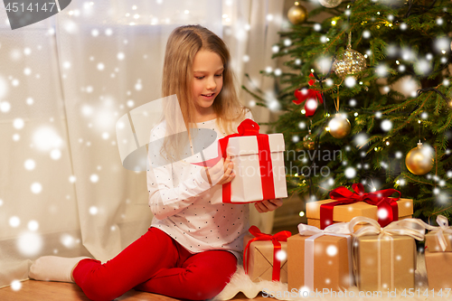 Image of smiling girl with christmas gift at home