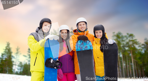 Image of happy friends in helmets with snowboards outdoors