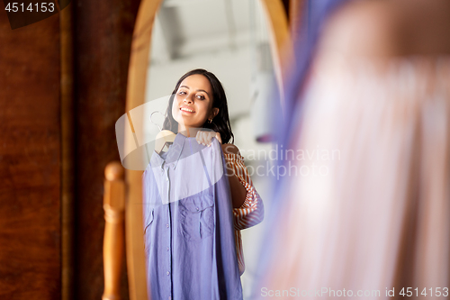 Image of woman with dress at vintage clothing store mirror