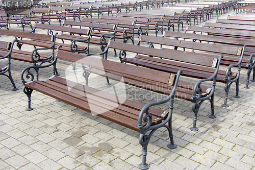 Image of Lot of Rows of empty brown wooden benches 