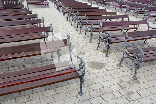 Image of Lot of Rows of empty brown wooden benches 