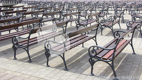 Image of Lot of Rows of empty brown wooden benches 