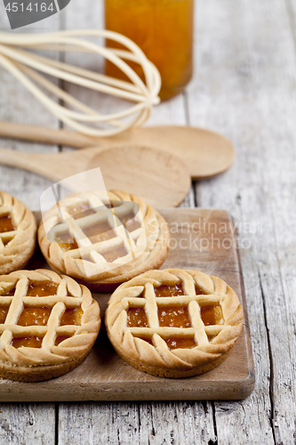 Image of Fresh baked tarts with marmalade or apricot jam filling and on c