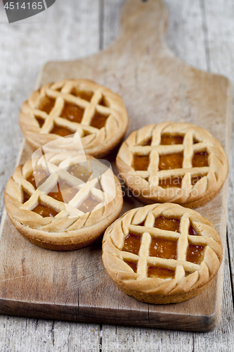 Image of Fresh baked tarts with marmalade or apricot jam filling on cutti