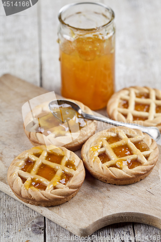 Image of Fresh baked tarts with marmalade filling and apricot jam in glas
