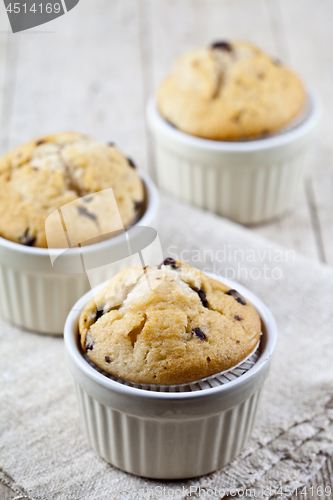 Image of Homemade fresh muffins on ceramic white bowls on linen napkin on