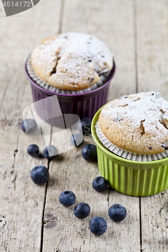 Image of Two homemade fresh muffins on ceramic green and purple bowls wit