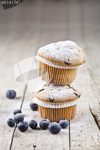 Image of Two fresh homemade muffins with blueberries on rustic wooden tab