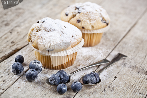 Image of Homemade fresh muffin with sugar powder, vintage spoons and blue