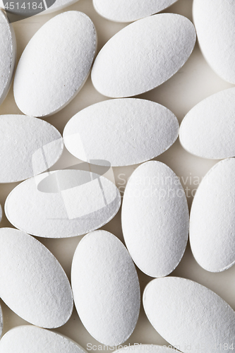 Image of Pile of white drug pills laying on white background