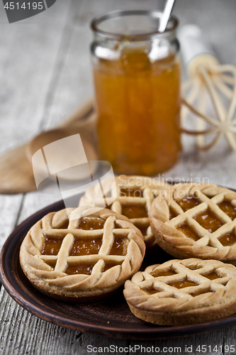 Image of Fresh baked tarts with marmalade or apricot jam filling and on c