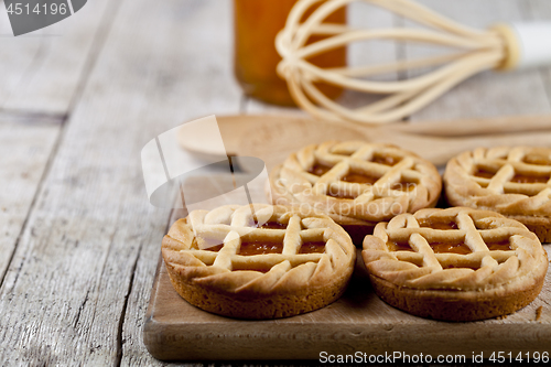 Image of Fresh baked tarts with marmalade or apricot jam filling and on c