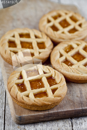 Image of Fresh baked tarts with marmalade or apricot jam filling on cutti