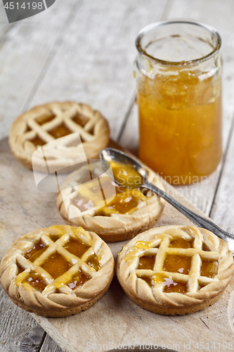 Image of Fresh baked tarts with marmalade filling and apricot jam in glas