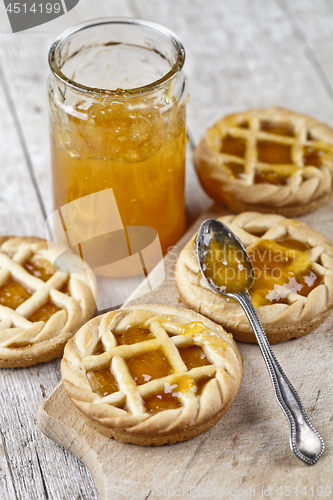 Image of Fresh baked tarts with marmalade filling and apricot jam in glas