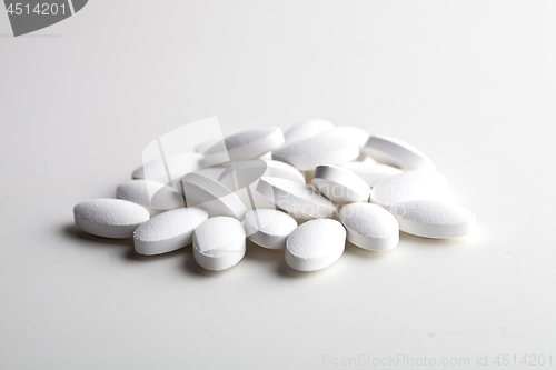 Image of Pile of white drug pills laying on white background. Medical con