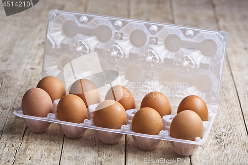 Image of Fresh chicken eggs on plastic container on rustic wooden table.