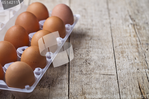 Image of Fresh chicken eggs on plastic container on rustic wooden table b