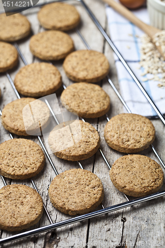 Image of Baking grid with fresh oat cookies on rustic wooden table backgr