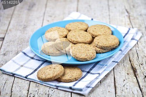 Image of Fresh baked oat cookies on blue ceramic plate on linen napkin on