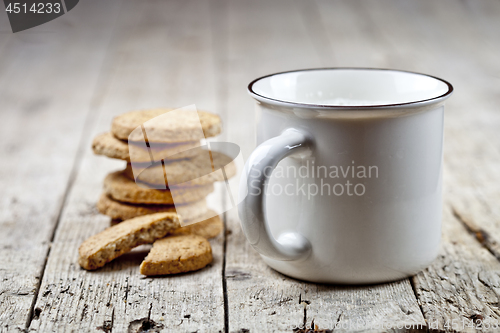 Image of Cup of milk and stack of fresh baked oat cookies on rustic woode