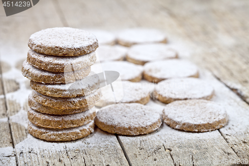 Image of Fresh baked oat cookies with sugar powder on rustic wooden table